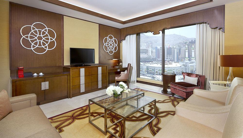 자발 오마르 메리어트 호텔, 마카 메카 외부 사진 The photo shows a luxurious hotel room or living area. It features elegant furnishings, including a sofa, a coffee table with a decorative pattern, and a comfortable armchair. A large window provides a view of the outside landscape, which appears to 