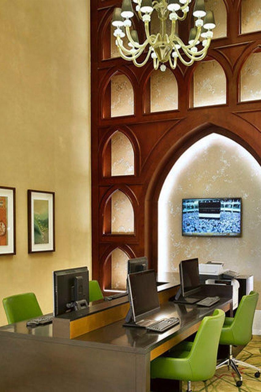 자발 오마르 메리어트 호텔, 마카 메카 외부 사진 The photo shows an interior space that features a blend of modern and traditional design elements. On one side, there are several workstations with computers, and on the opposite wall, there is a large television screen displaying a sports event. The